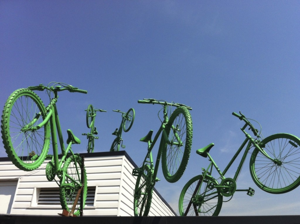 Five green bikes leap from two levels of the rooftop of Putney Leisure Centre